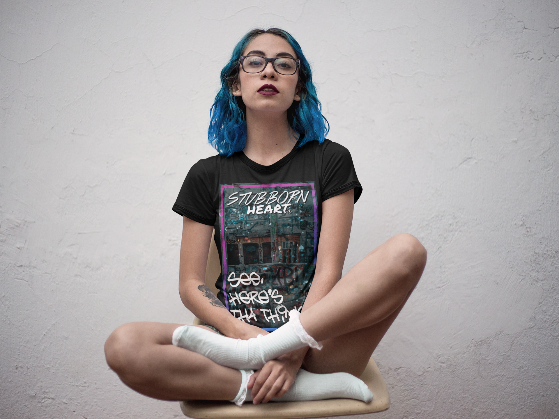 Female punk model with blue hair wearing and promoting a black 'See Here's Tha Thing!' T-Shirt by STUBBORN HEART Apparel