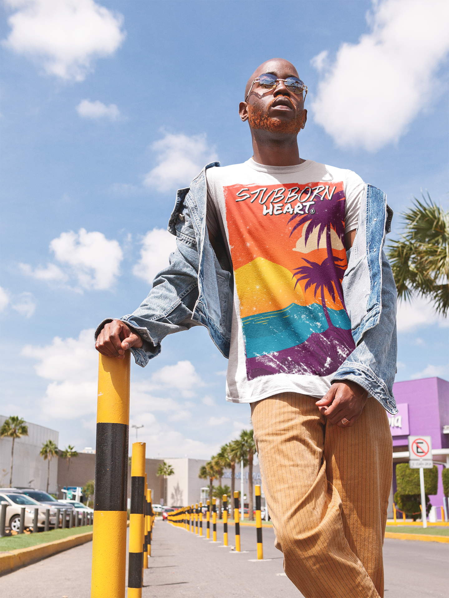 Cool Black Male model wearing a white STUBBORN HEART Apparel tee design called Sunset, in LA